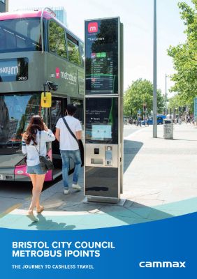 A man and woman use a sleek metrobus ticket machine on a sunny street. A double-decker bus is nearby. The scene promotes cashless travel.